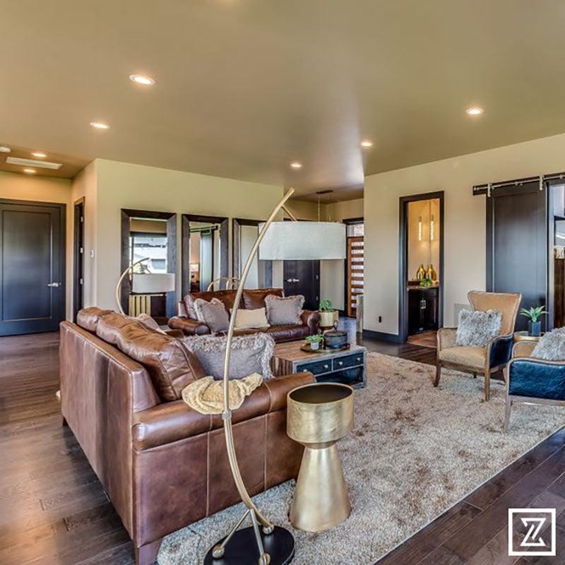 A living with hardwood flooring, a beige plush area rug, with brown leather furniture, designed by Kate Loeb, Designer at Standard Paint & Flooring.