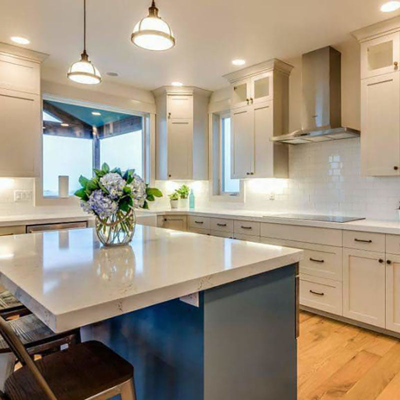 A renovated kitchen with white cabinets and natural hardwood flooring from Standard Paint & Flooring.