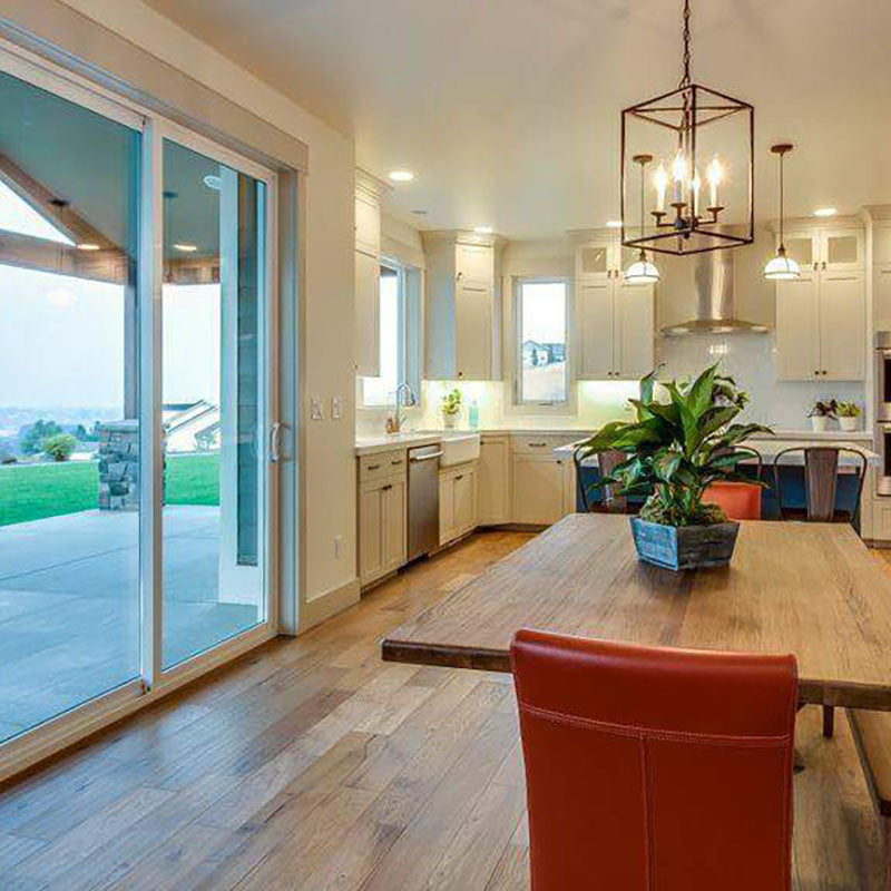 View from the back of a kitchen with natural hardwood flooring, white kitchen cabinets and a light wooden table with a red leather chair, designed by Kate Loeb, Designer at Standard Paint & Flooring.