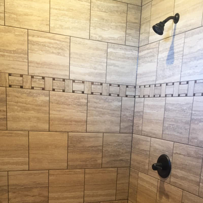 Close up view of inside a shower with a brown ceramic tile design from Standard Paint & Flooring.