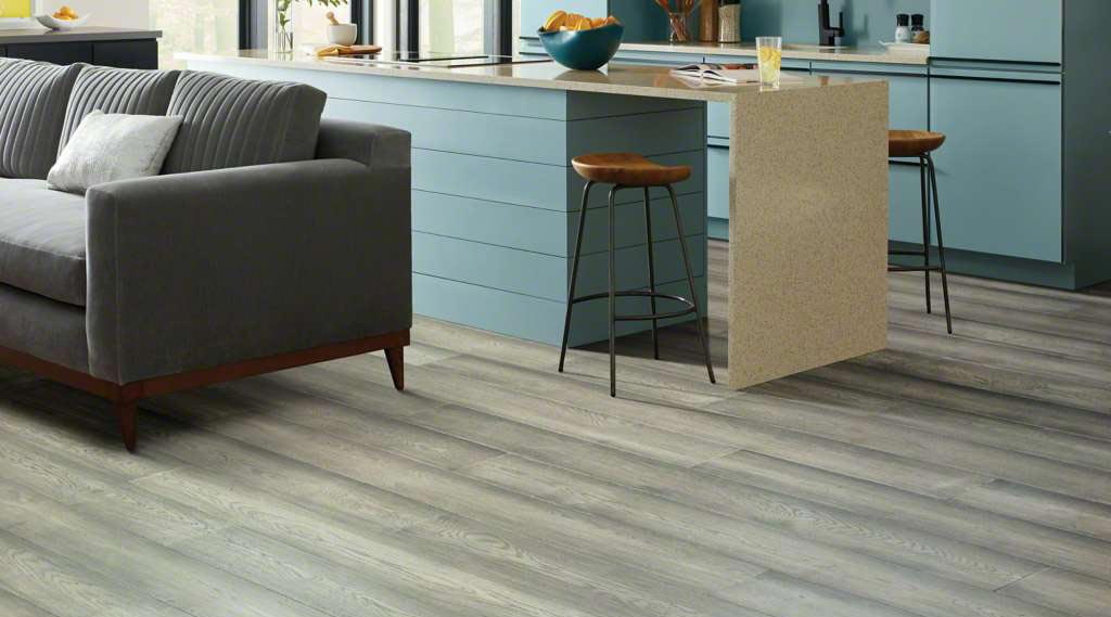 Grey wide plank hardwood flooring with a dark grey couch.  