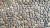 Close up of a wall with natural colored pebble tiles.